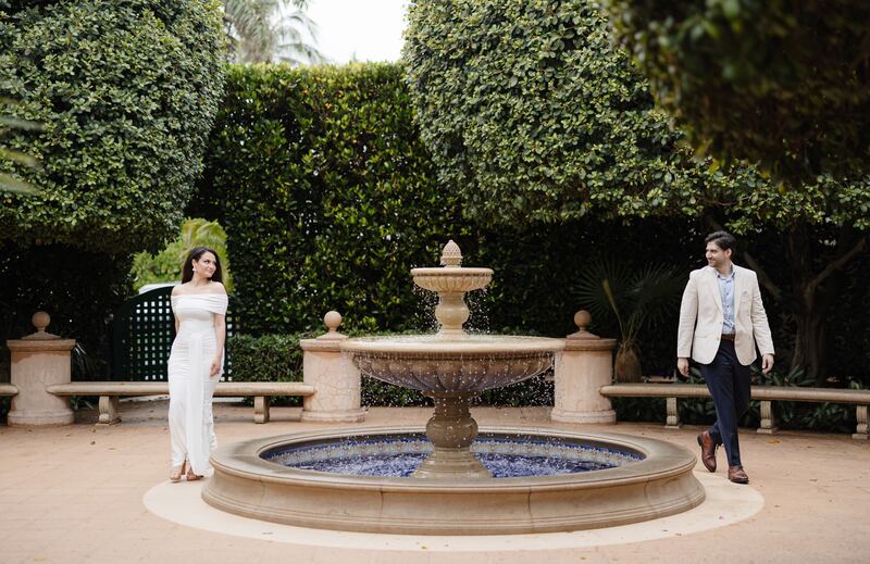 Iviani and Joey on either side of a blue-tiled fountain