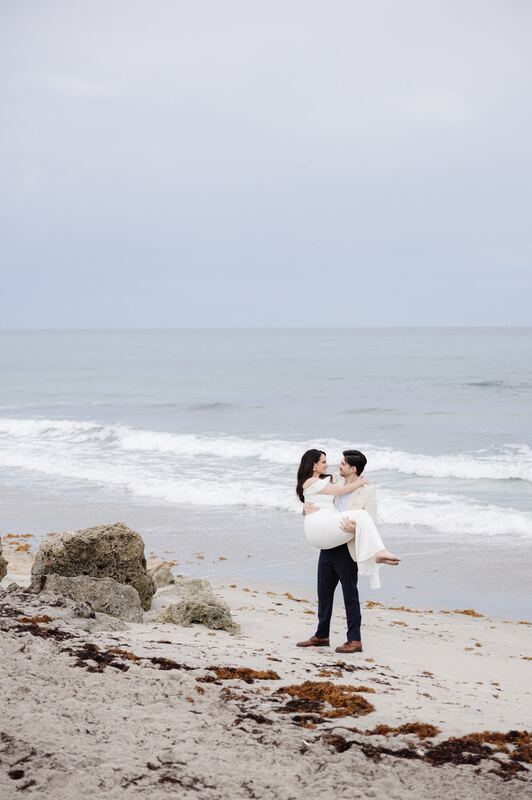Iviani and Joey embracing on the beach at the water’s edge